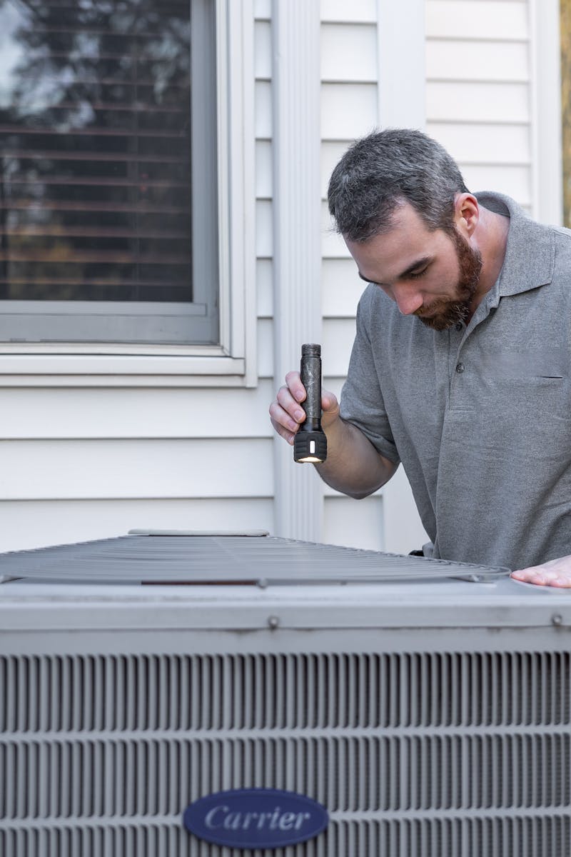 A technician inspects an outdoor HVAC unit for maintenance.